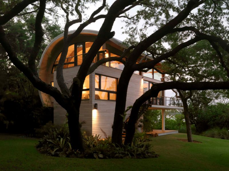 Wave shaped Florida home behind an oak