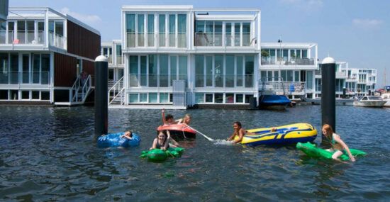 Kids swim in front of floating homes