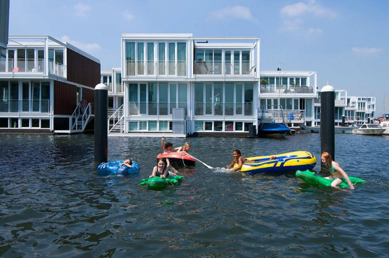 Kids swim in front of floating homes