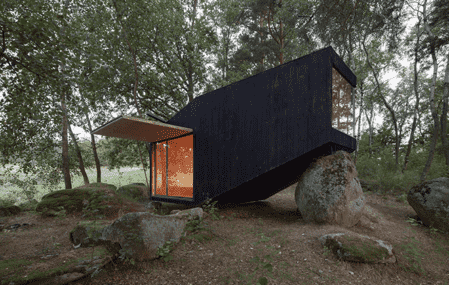 modern forest hut black balanced on rock