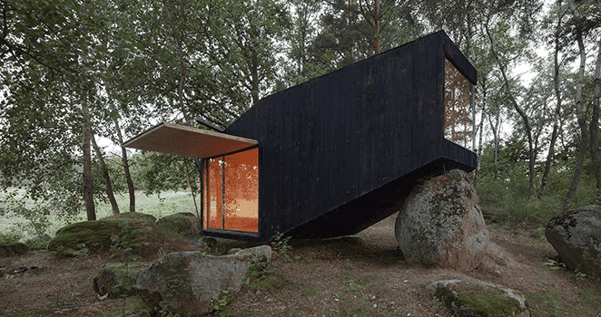 modern forest hut black balanced on rock
