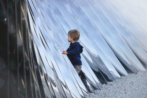 A small child touching the surface of the NAWA Pavilion