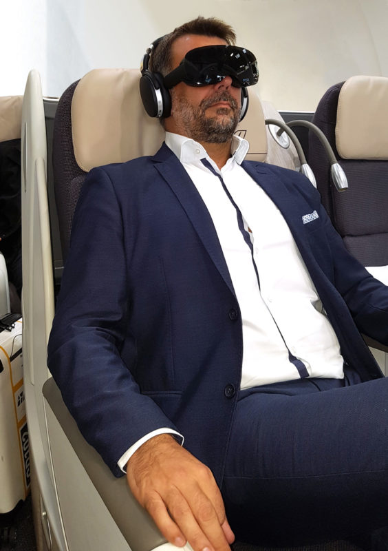 First class passenger seated and wearing an Allosky VR headset.
