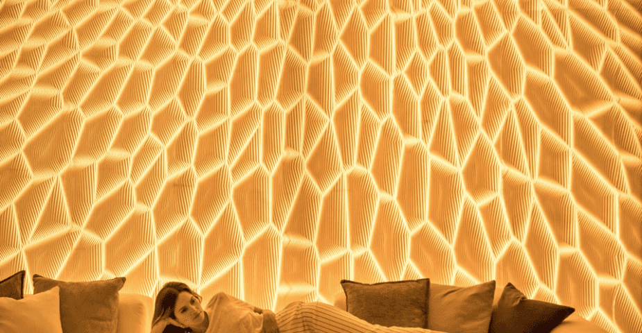 A woman lying down in front of San Vicente's 3D-Printed Light Wall.