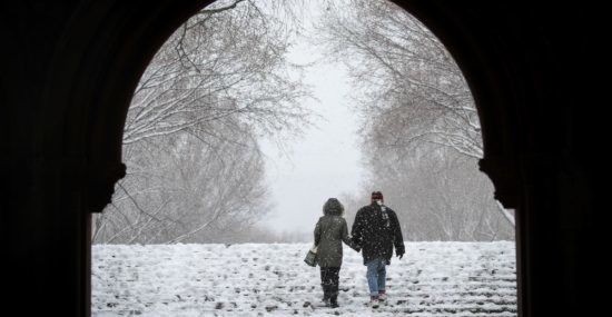 A couple walking together under an arch in the snow