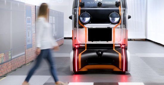 A self-driving "Eye Pod" vehicle waiting at a crosswalk.
