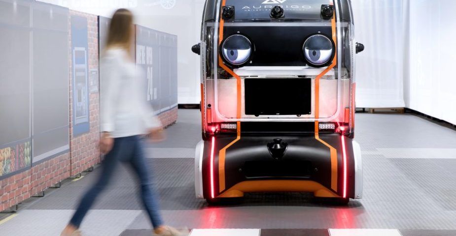 A self-driving "Eye Pod" vehicle waiting at a crosswalk.