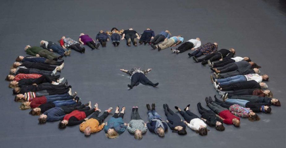 People lying down in a circle on the heat-sensitive floor featured in Tania Bruguera's new interactive installation, "10,145,196."