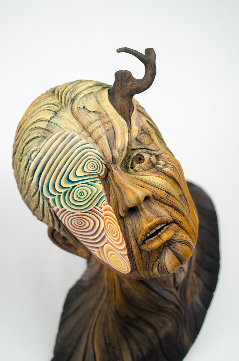 A ceramic sculpture by Christopher David White, this one depicting the bust of a man whose face is obscured by several different colors.