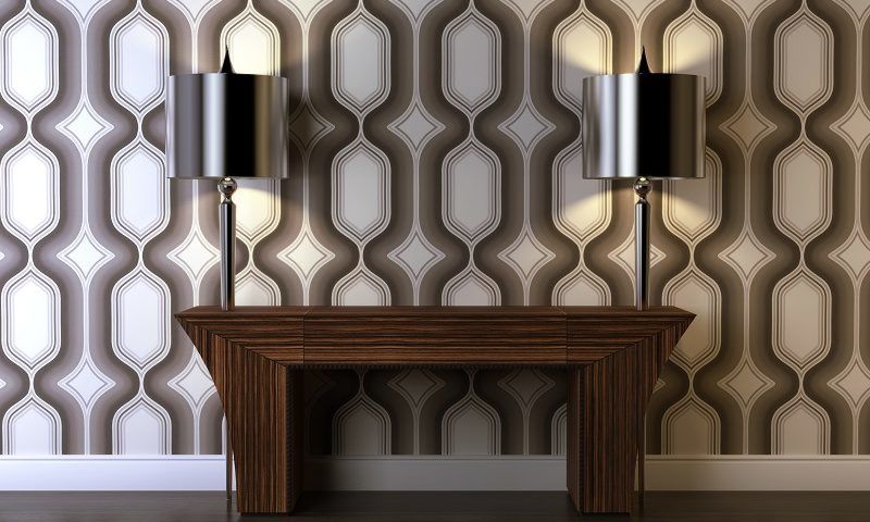 A small slice of an Art Deco decor scheme, featuring two steel lamps, a nightstand, and vintage wallpaper.