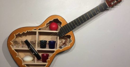 An acoustic guitar hollowed out and upcycled into a shelf.