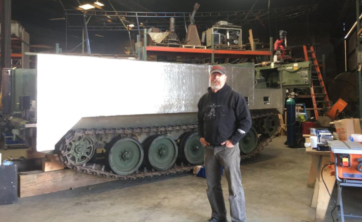 Former MythBuster Jamie Hyneman standing in front of his new firefighting "Sentry" tank.