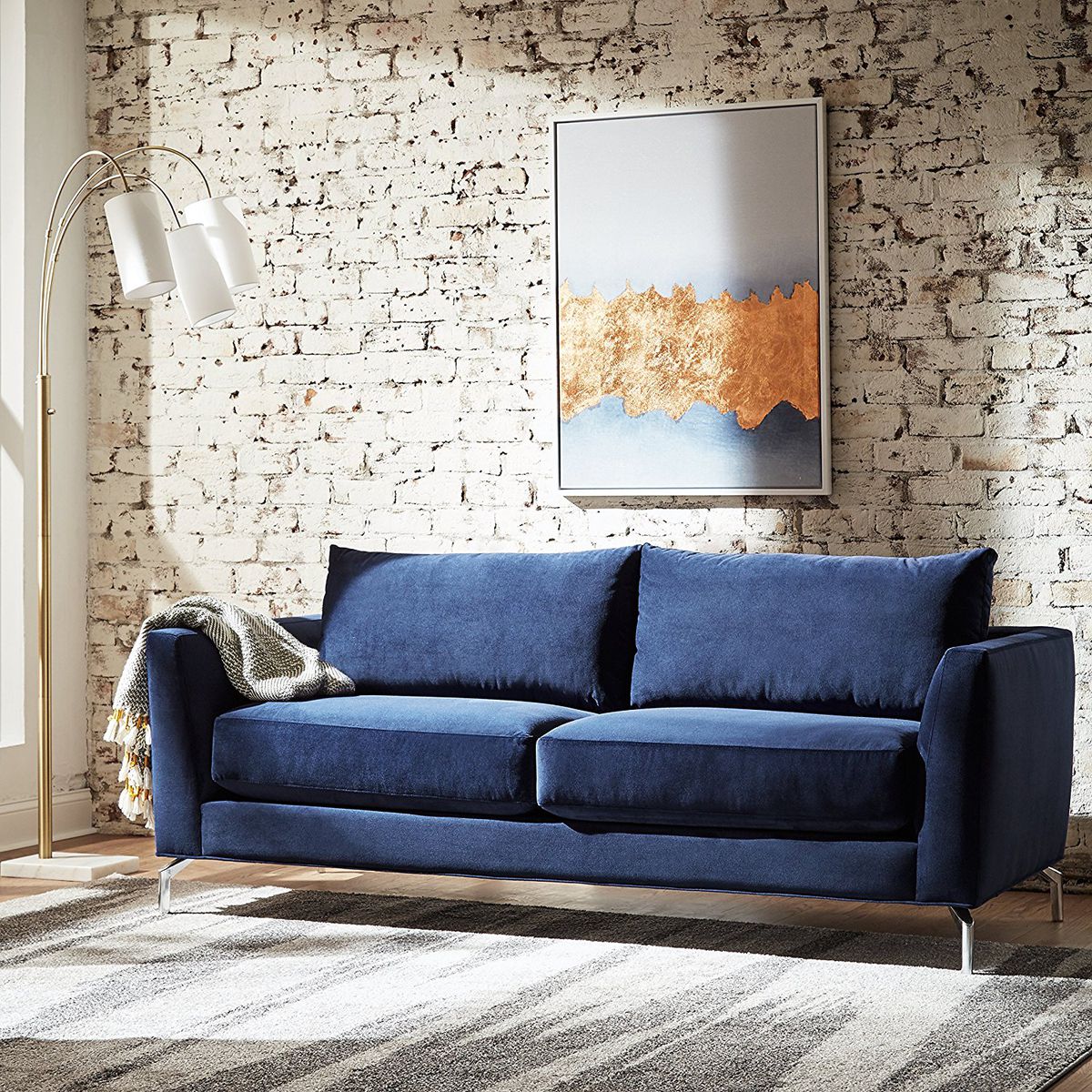 One of Amazon's navy blue "Rivet" couches set up in a living space.