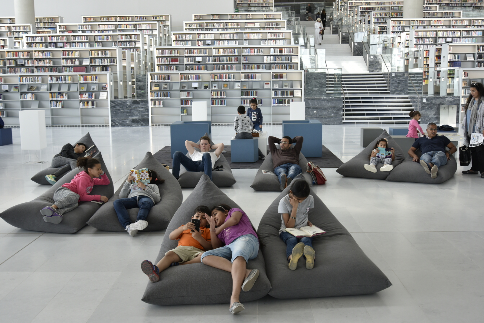 People reading and relaxing on beanbag chairs inside the new Qatar National Library.