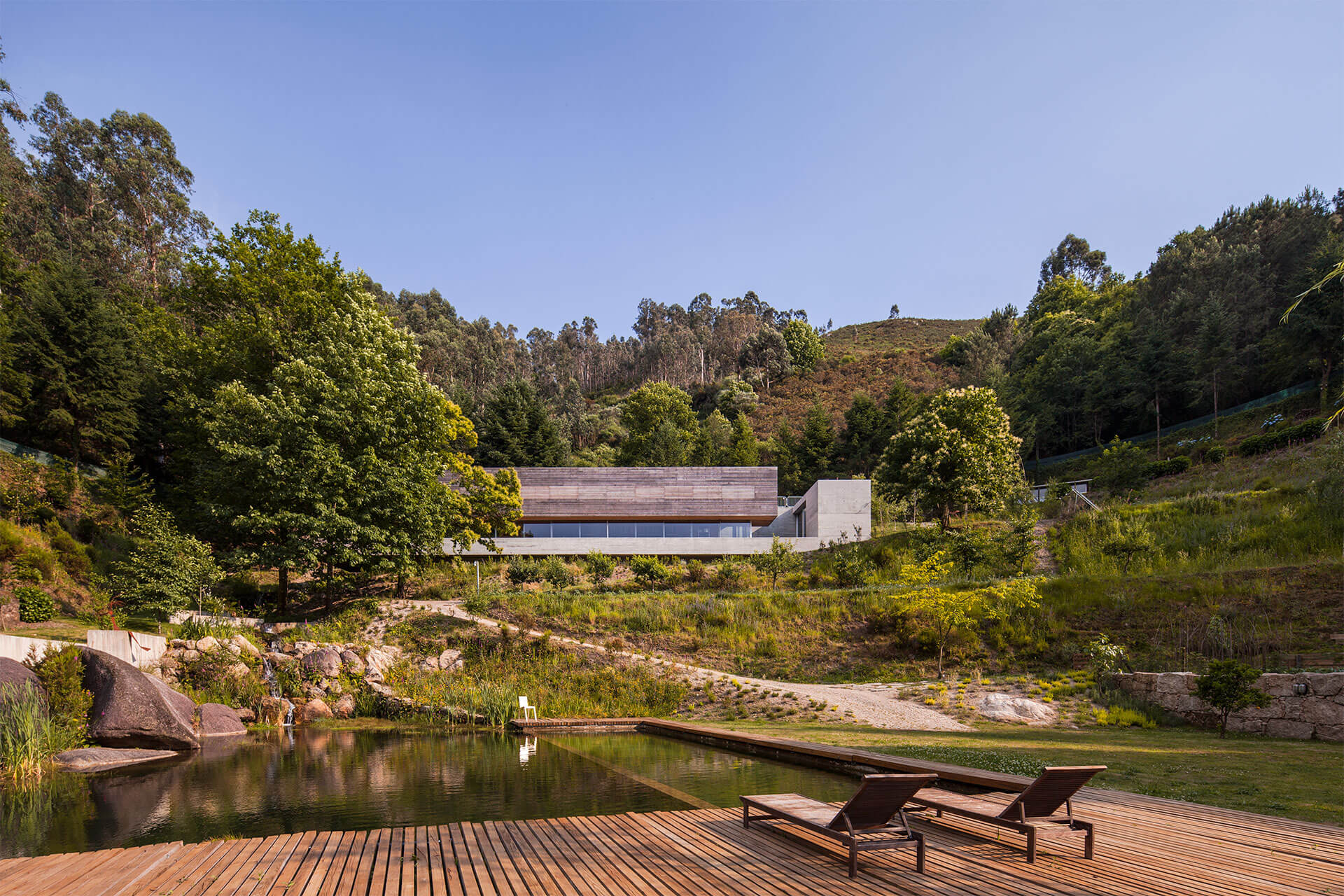 The Gerês House's lower wooden deck and pond area, with the house itself visible in the background. 
