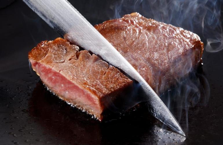 Knife cutting into steak. 