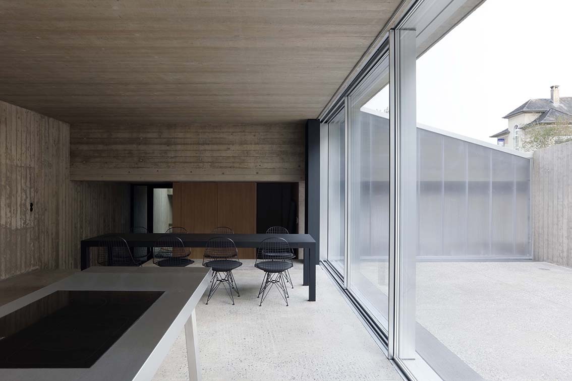 The open plan dining/living areas inside the Hercules House, with the home's large operable glass wall visible on the right.