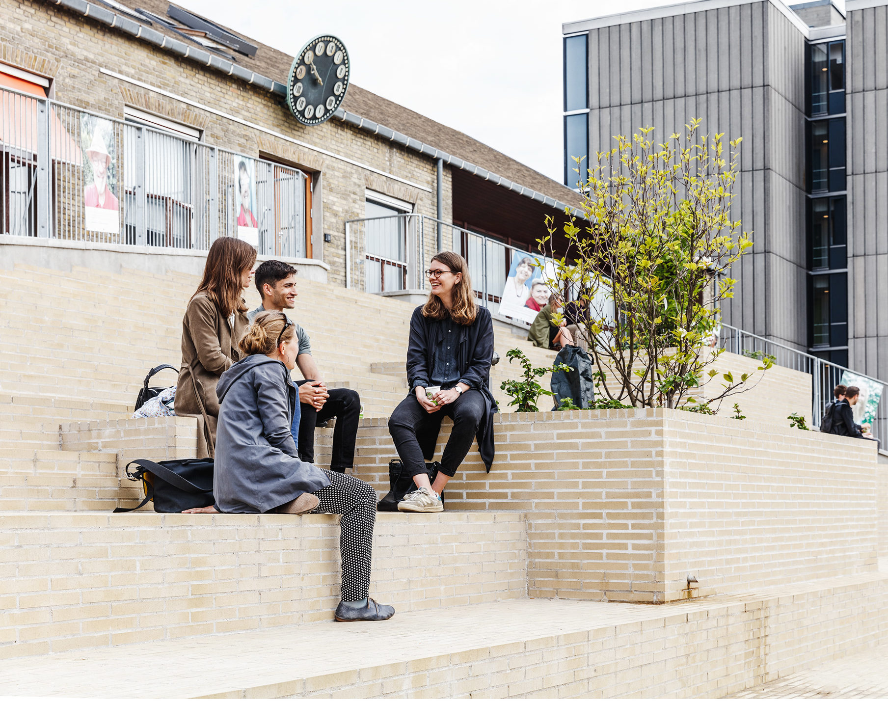 A group of friends sitting on the Red Cross Volunteer House's brick rooftop plaza.