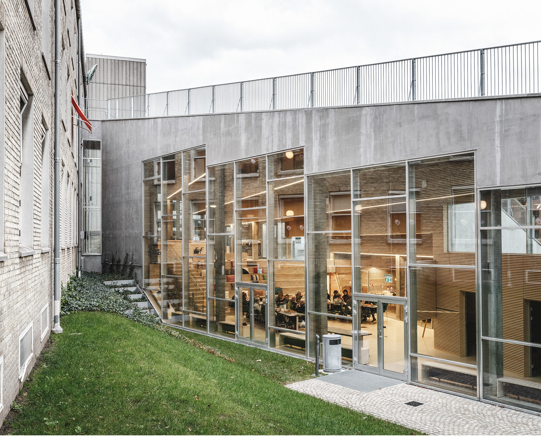 External view of the Red Cross Volunteer House's auditorium, as situated beneath the structure's slanted brick plaza.