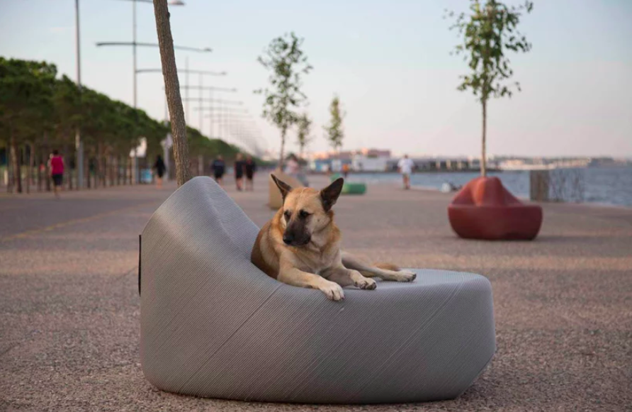 Dog sitting on a bench created from recycled plastic waste as part of The New Raw's "Print Your City!" initiative. Located in Thessaloniki, Greece. 