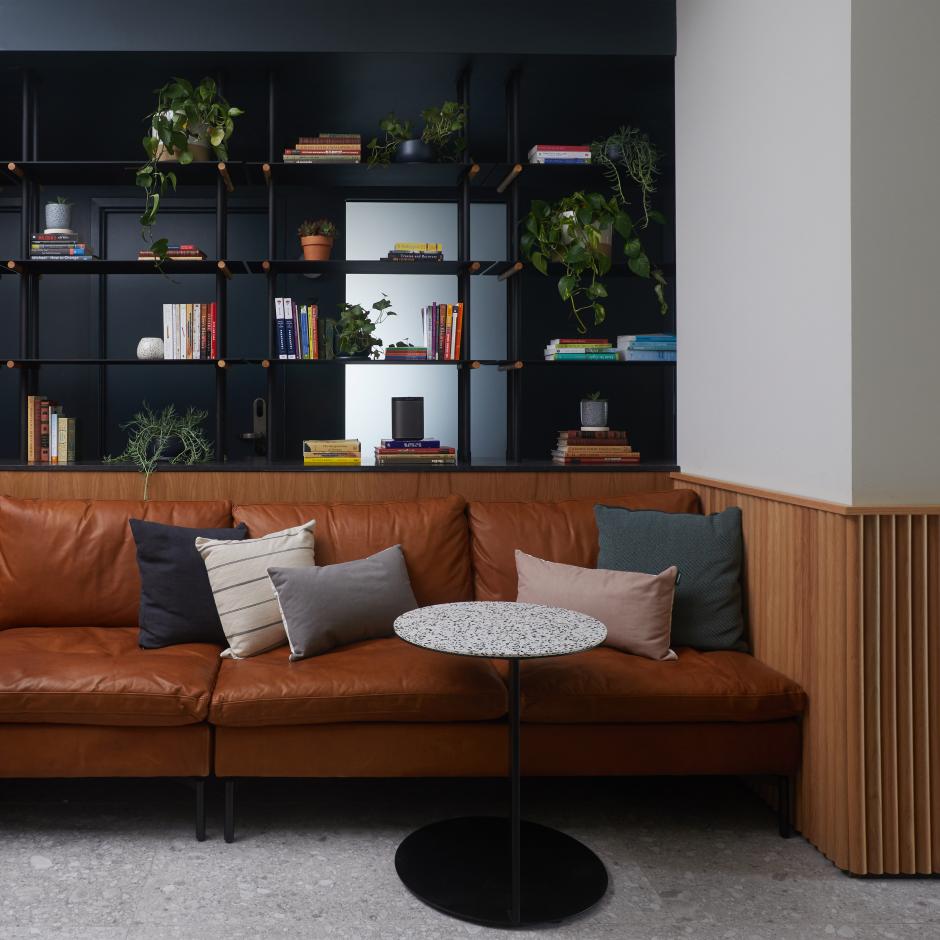 The waiting area at the new Alma co-working facility in New York City, complete with sleek black shelving and comfortable brown leather couches. 