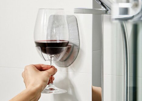 The Sipski Wine Glass Holder mounted to a shower wall, with a glass of red wine nestled firmly inside it.