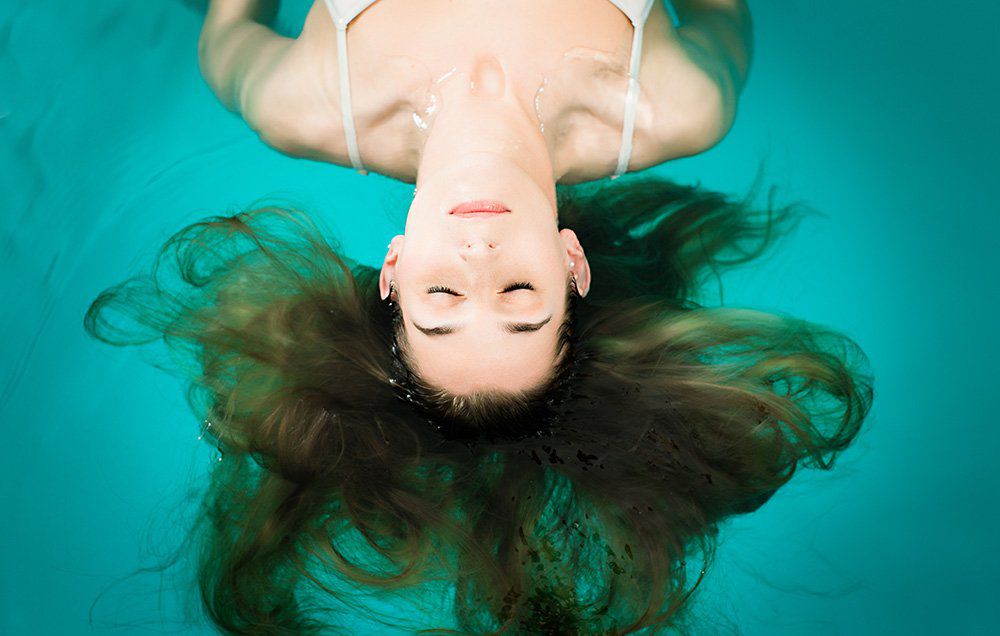 Young woman relaxing as she drifts in a flotation tub. 