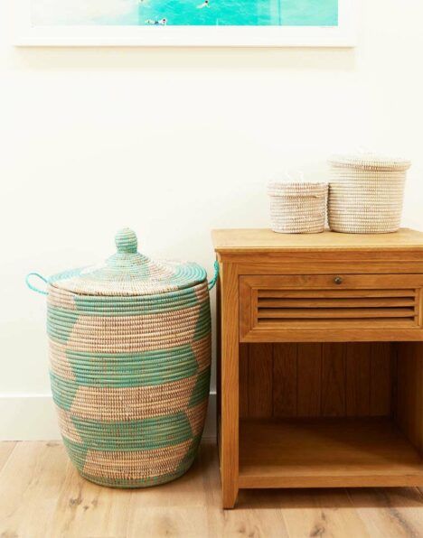 A colorful natural fiber basket from Senegal placed next to a nightstand.