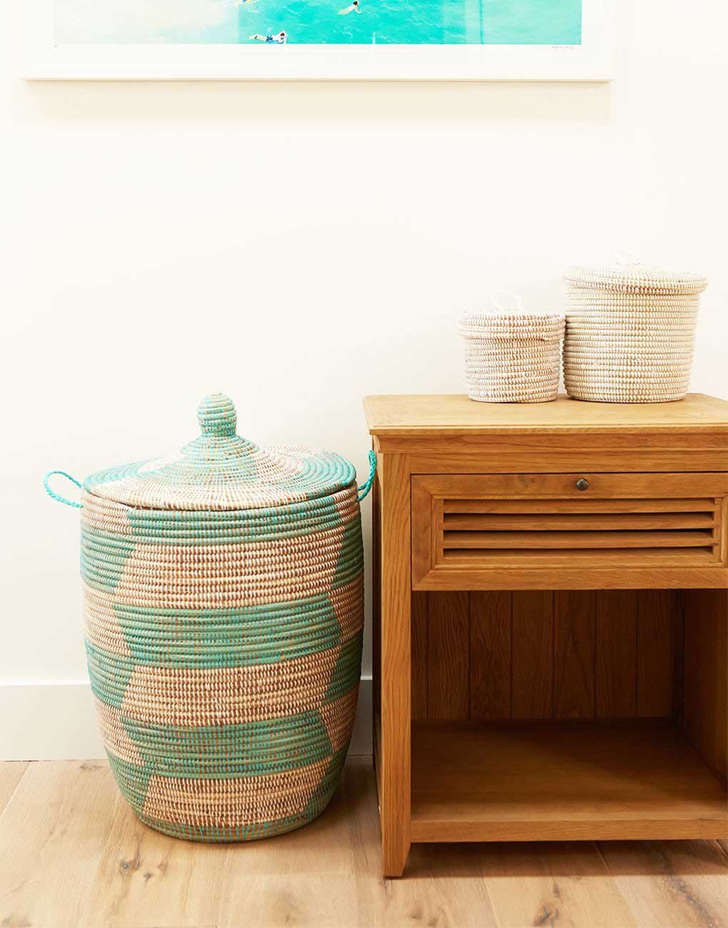 A colorful natural fiber basket from Senegal placed next to a nightstand.