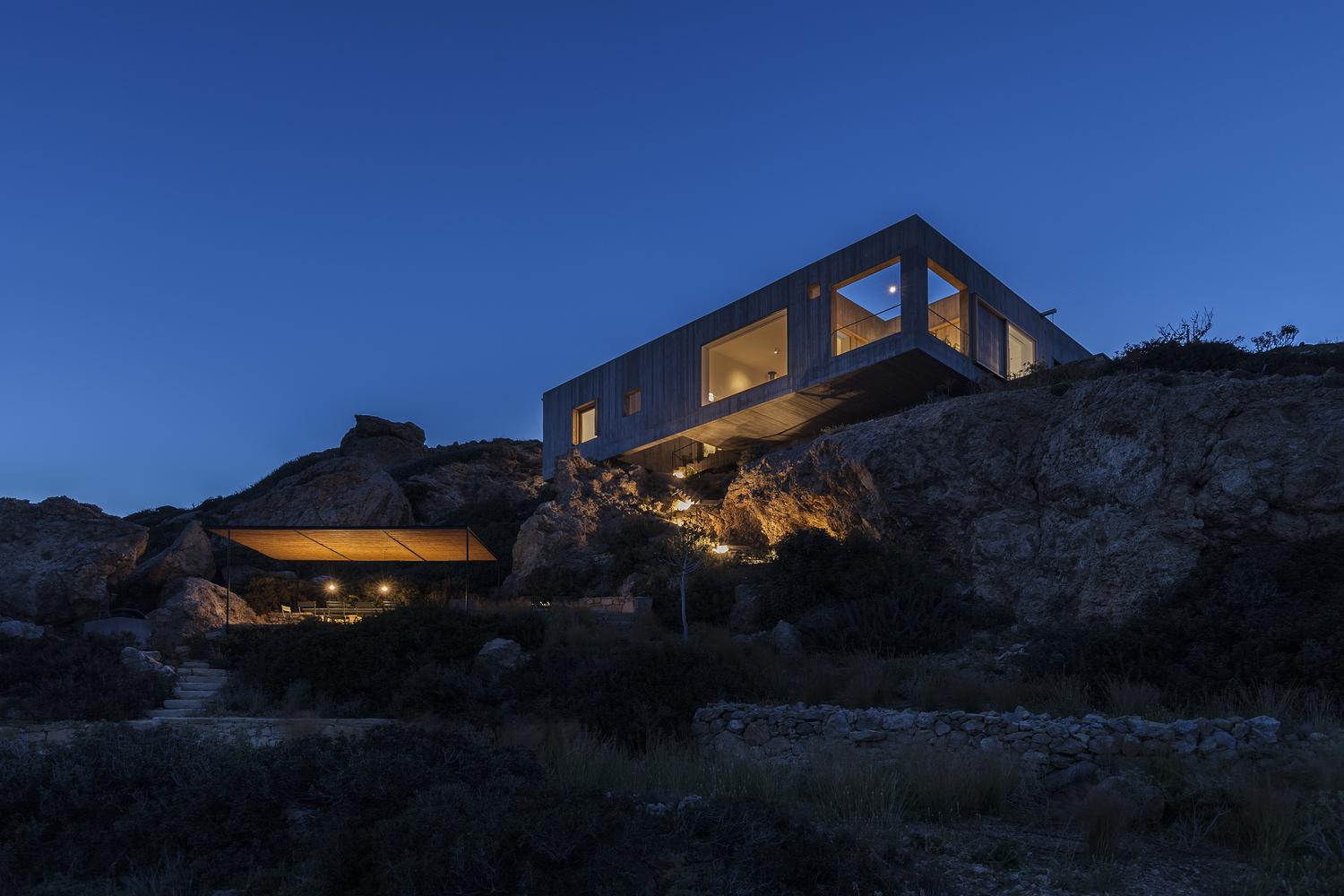 Exterior nighttime shot of the cliffside "Patio House" in Greece. 
