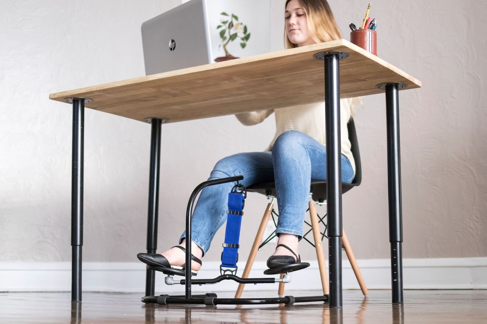 Woman sits at her desk while staying active with her freestanding HOVR Desk Swing. 
