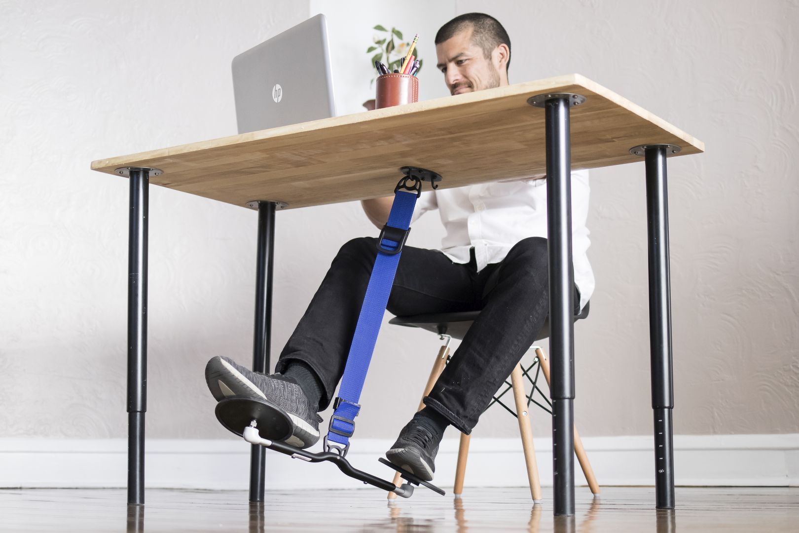 Man sits at his desk while staying active with his HOVR Desk Swing. 