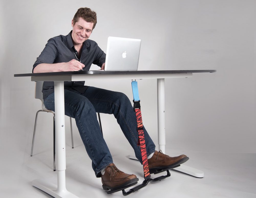 Man sits at his desk while staying active with his HOVR Desk Swing.