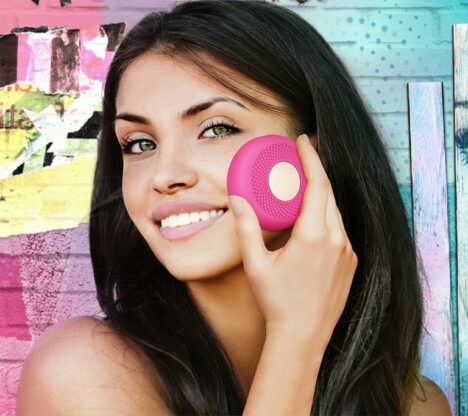 A young woman uses the Foreo UFO Smart Mask Treatment on her face.