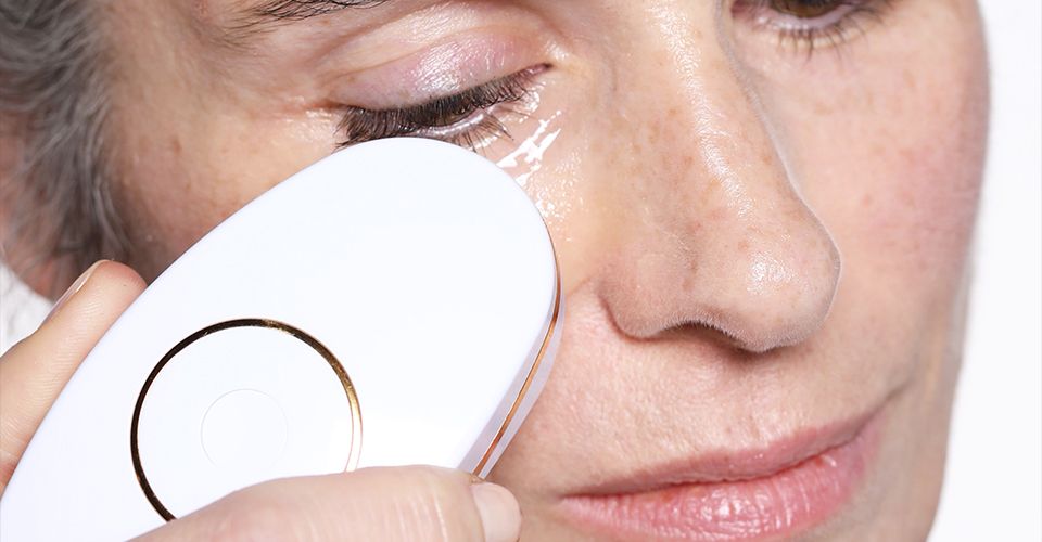 A woman uses the ZIIP Nano Current Facial Device on the skin under her eyes. 