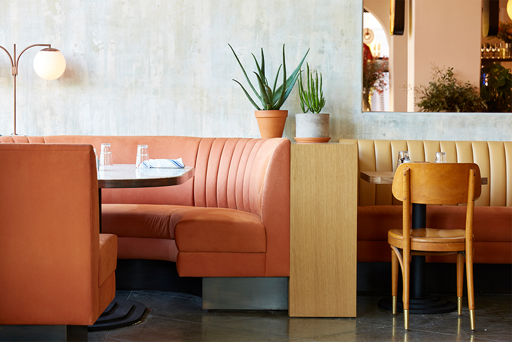 The coral and mustard-colored banquettes featured inside Five Leaves LA.