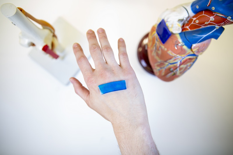 A human hand wearing an active adhesive dressing